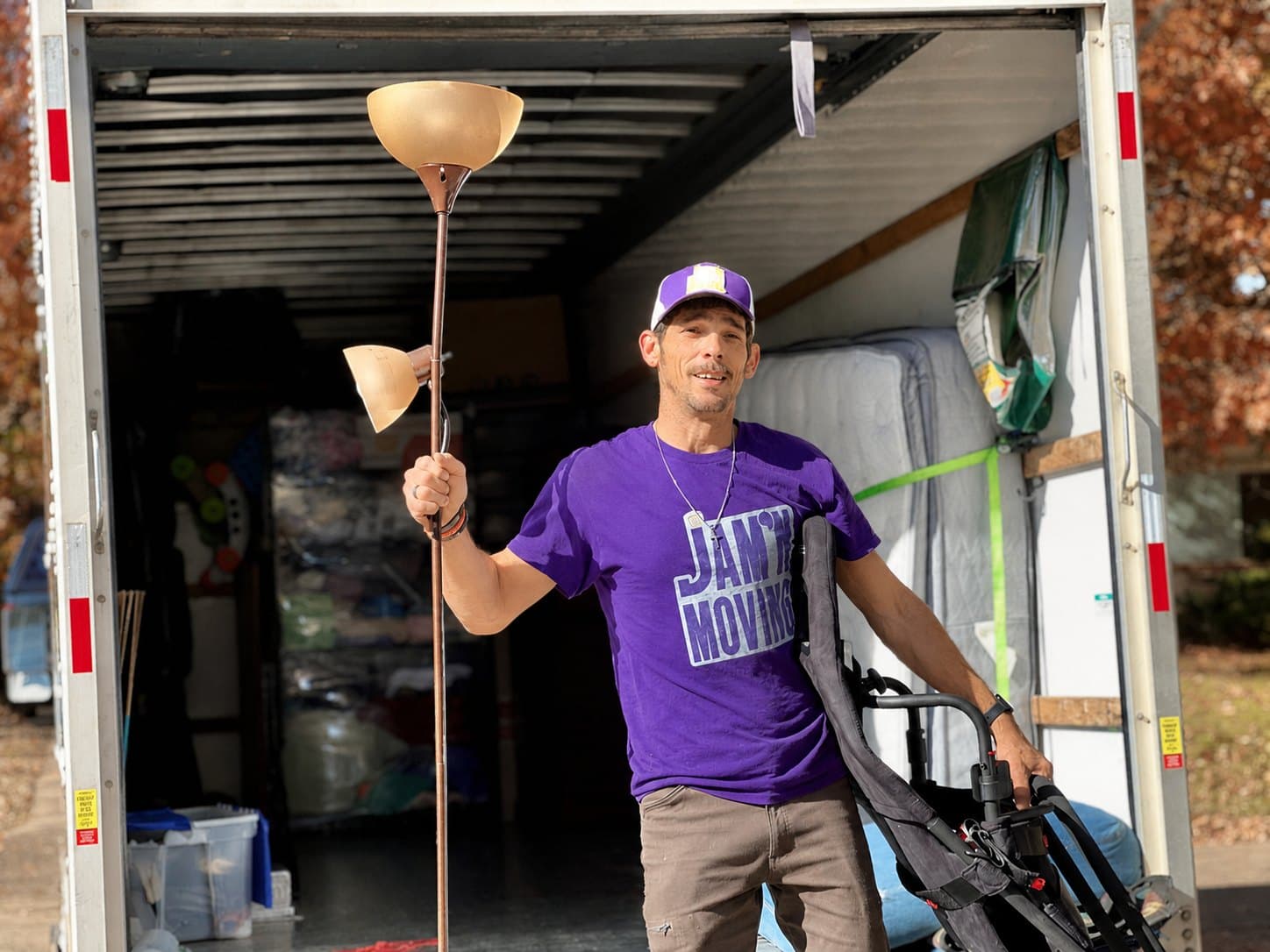 Chris Coots, owner of Jam'N Moving, unloading a lamp and hand truck from the back of a loaded moving truck